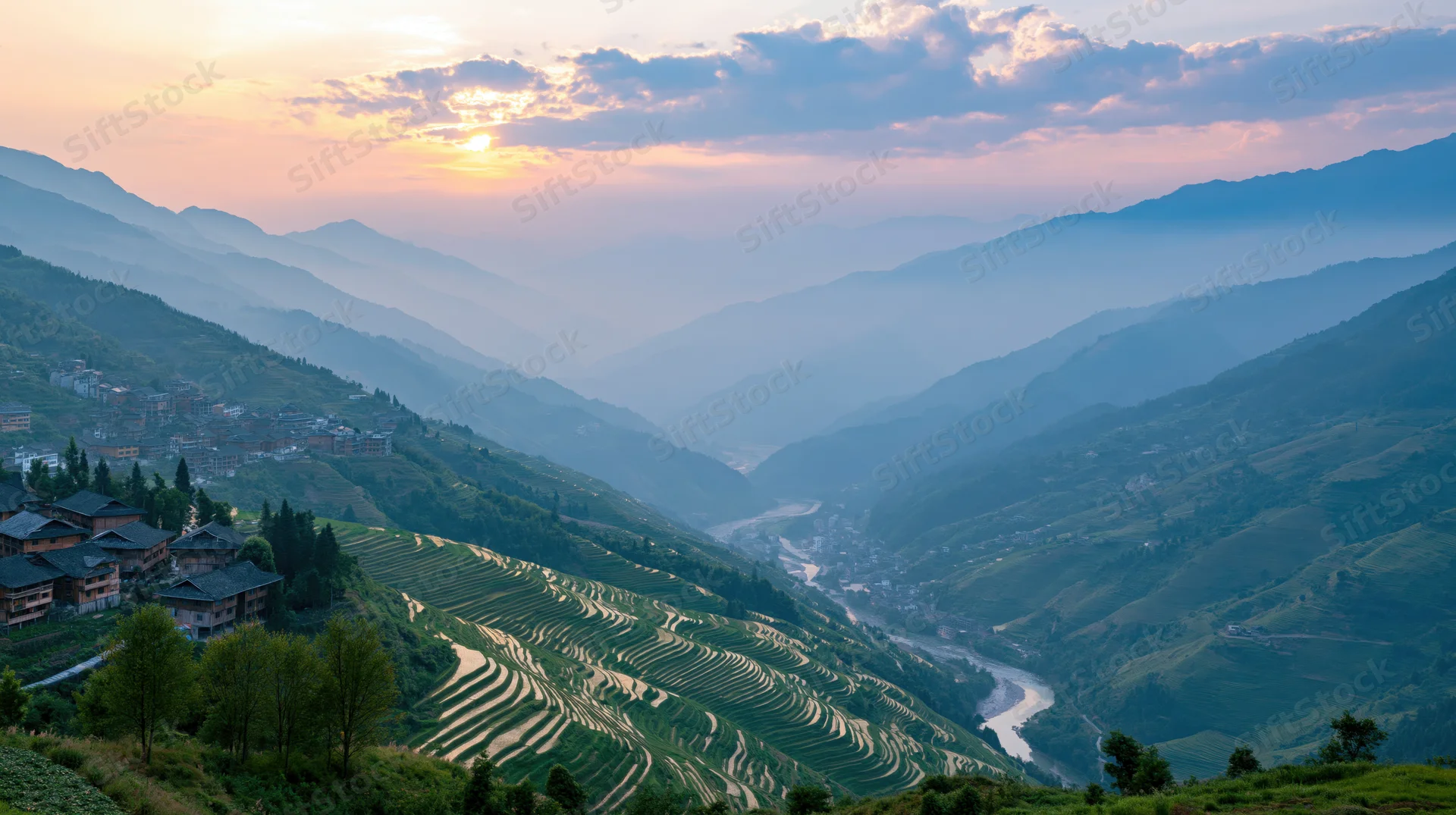 Rice terraces winding along mountain slopes at sunset with a river flowing through the valley and a village nestled above