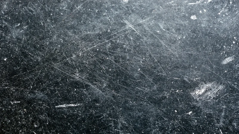 Close-up of a scratched and worn dark surface showing signs of use and age