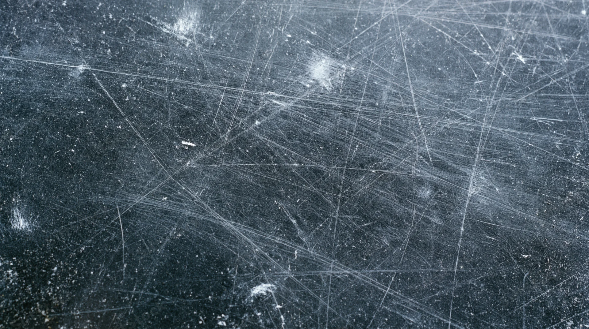 Scratched metal surface with intersecting wear marks and scattered debris