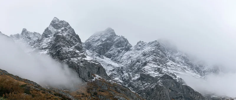 Snow-covered mountain peaks rising above misty clouds in alpine terrain