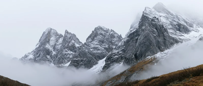 Snow-covered mountain peaks rising above fog in alpine landscape