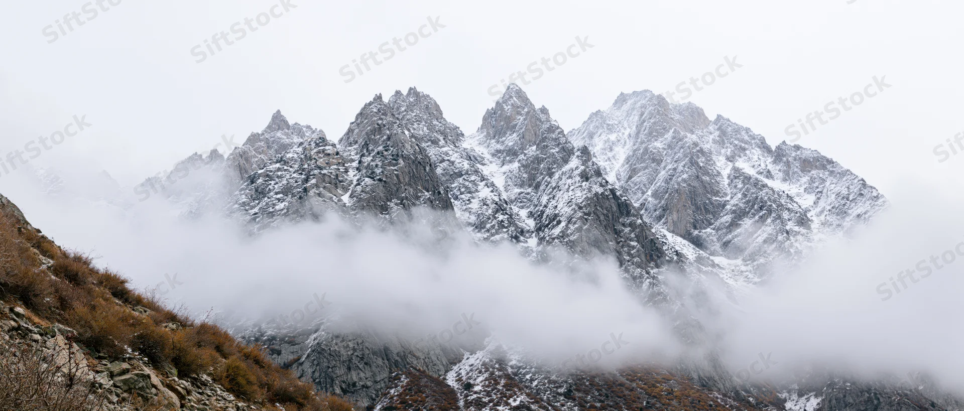 Snow-covered mountain peaks rising above clouds in alpine landscape