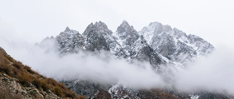 Snow-covered mountain peaks rising above clouds in alpine landscape