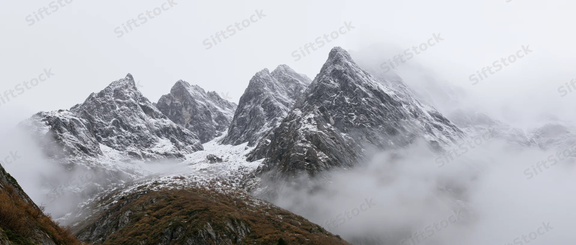 Snow-covered mountain peaks rising above fog in alpine landscape