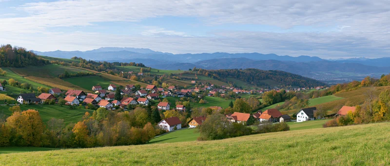Village nestled among rolling hills and autumn trees in a rural valley