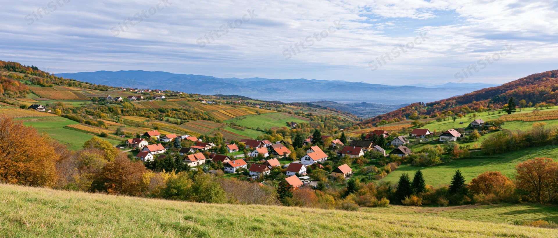 Village nestled among autumn-colored hills and vineyards in a rural countryside landscape
