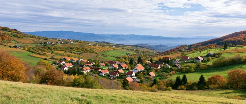 Village nestled among autumn-colored hills and vineyards in a rural countryside landscape