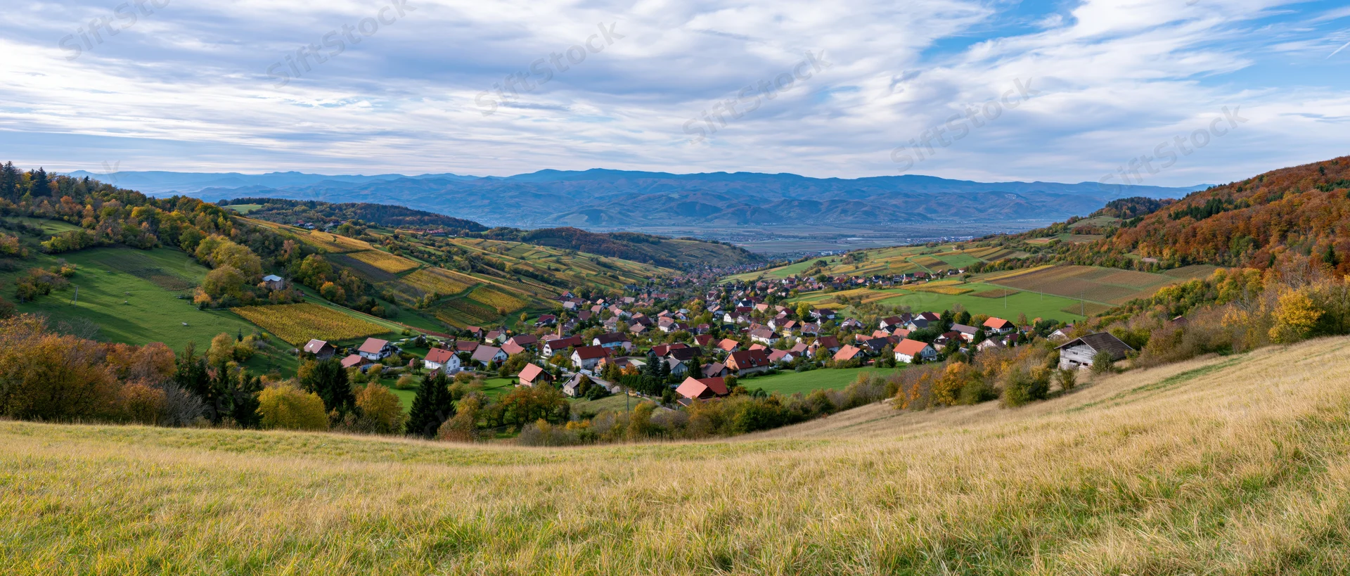 Village nestled in a valley surrounded by autumn-colored hills and farmland