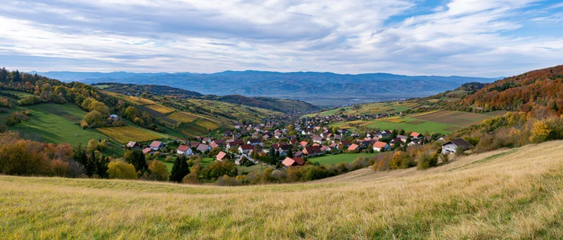 Village nestled in a valley surrounded by autumn-colored hills and farmland