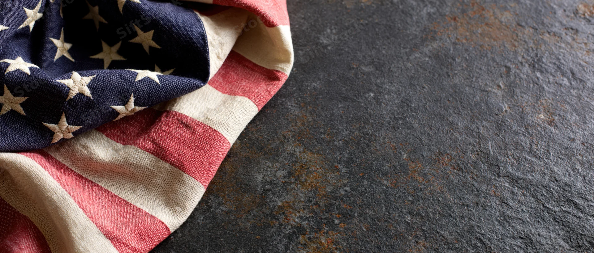 American flag draped on dark textured surface with copyspace