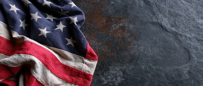 Crumpled american flag resting on dark textured stone surface with copyspace