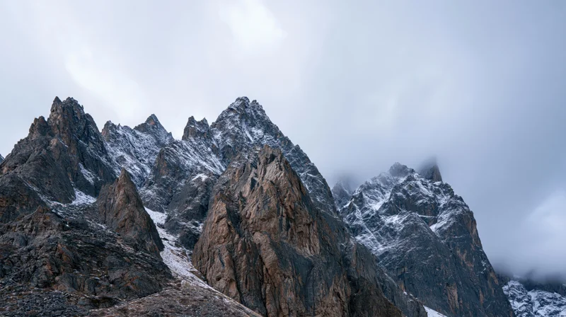 Jagged snow-dusted mountain peaks rising under overcast sky