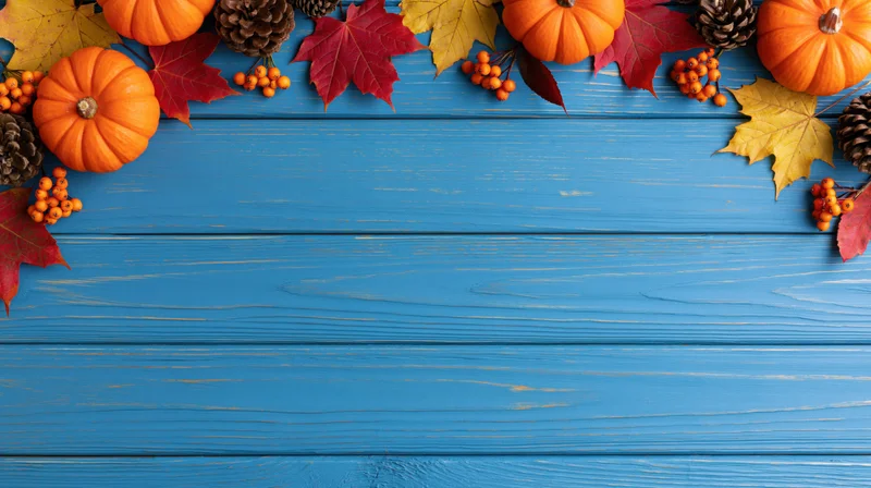 Autumn decorations arranged along the top of a blue wooden table, leaving copyspace below