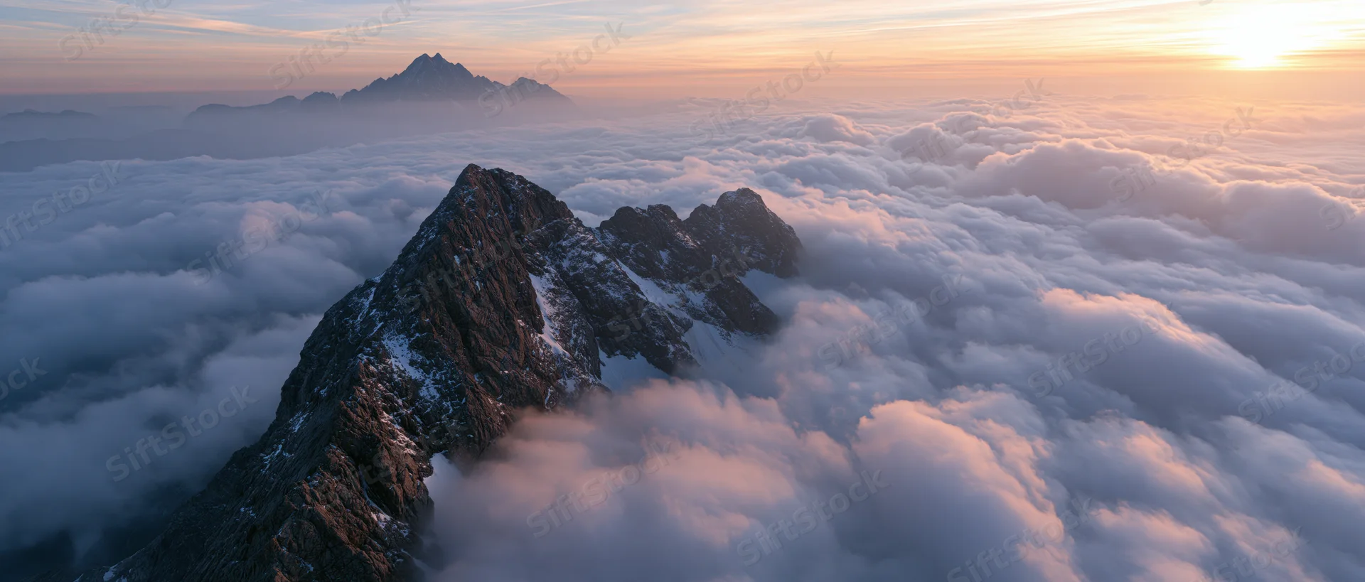Rocky mountain peak rising above a sea of clouds at sunrise
