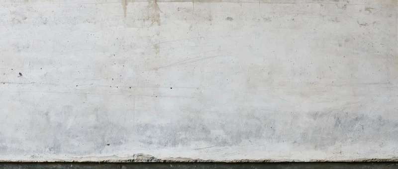 Weathered concrete wall surface with visible texture and stains, exterior building facade