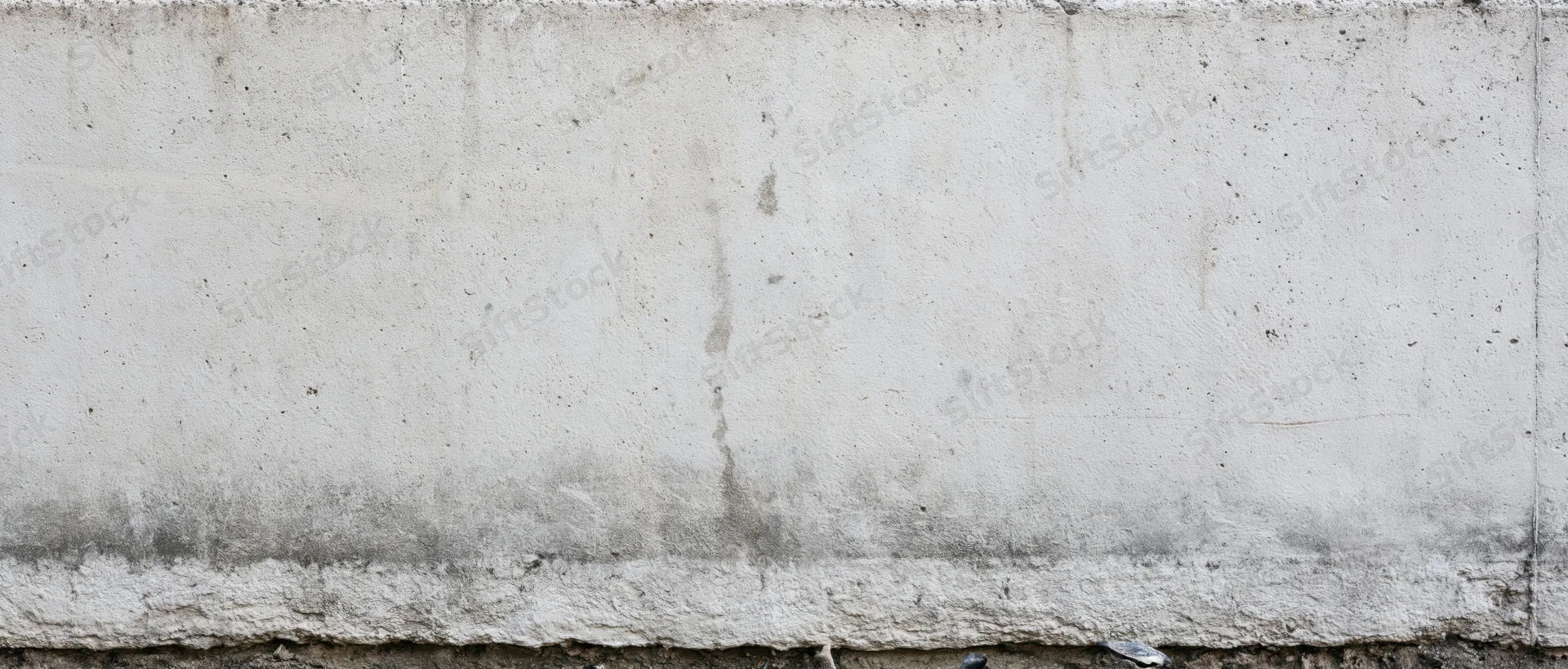 Weathered concrete wall with horizontal seam and damp stain at base