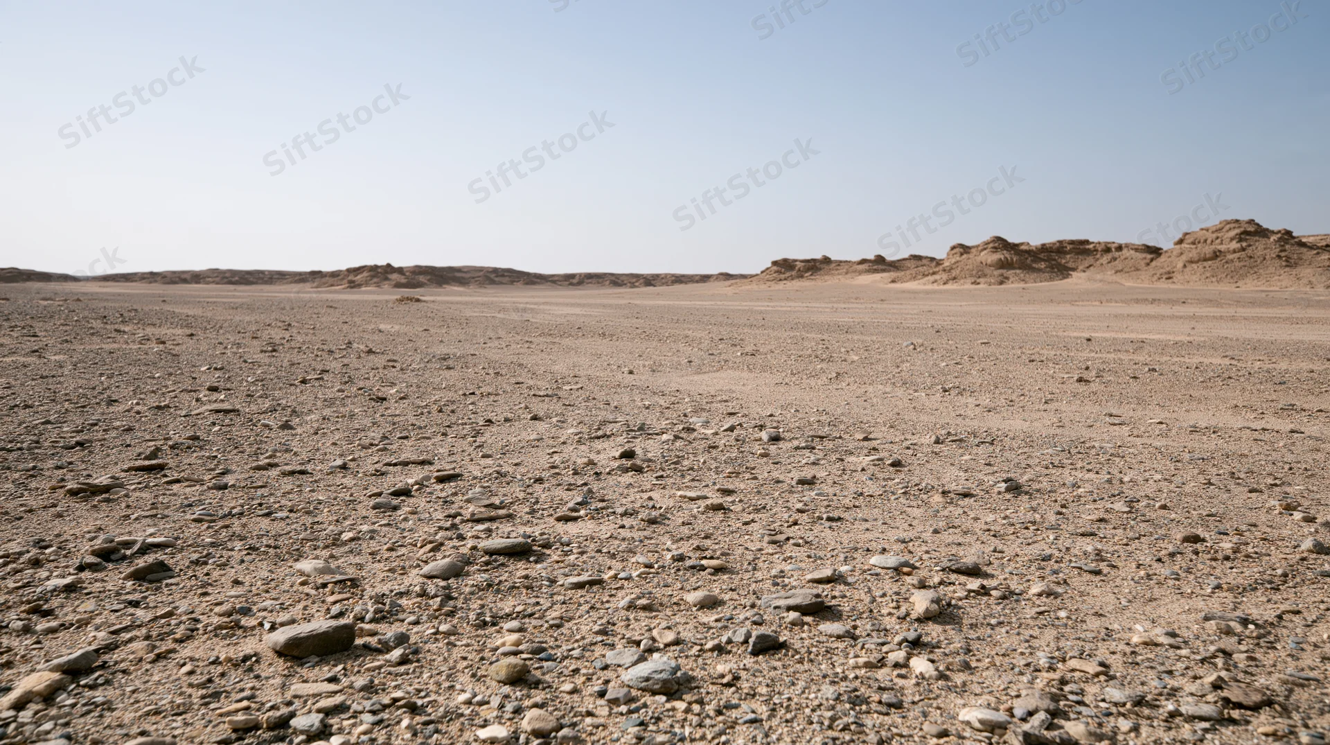 Rocky desert terrain stretching to distant buttes under clear blue sky