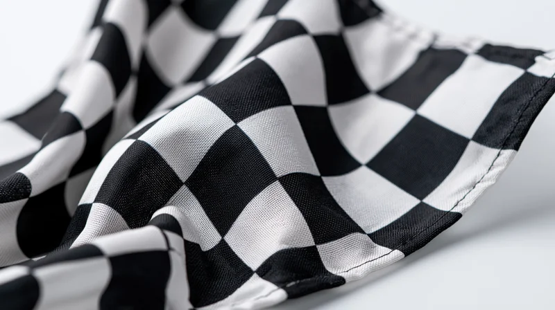 Checkered racing flag draped on a white surface with soft folds and visible stitching