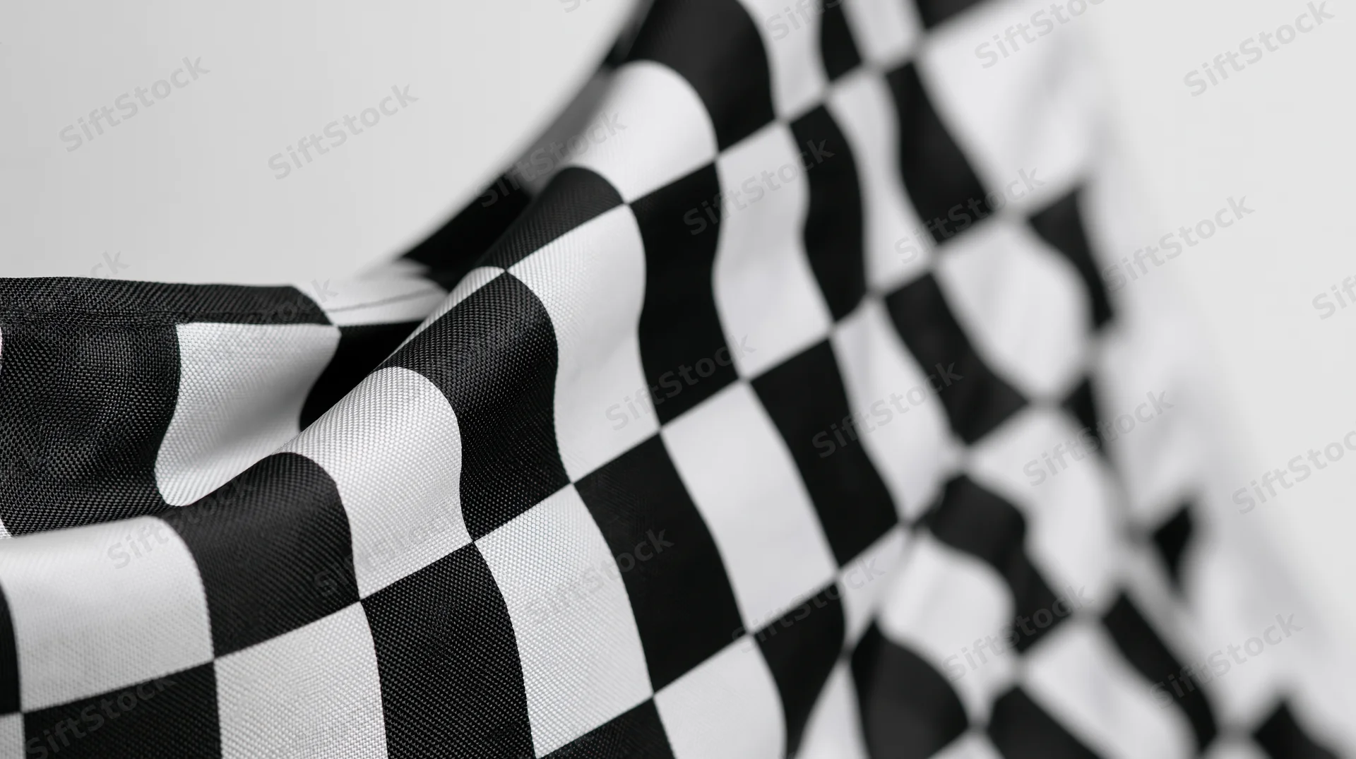 Closeup of a waving checkered racing flag with soft focus and shallow depth of field against a plain background