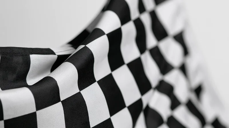 Closeup of a waving checkered racing flag with soft focus and shallow depth of field against a plain background