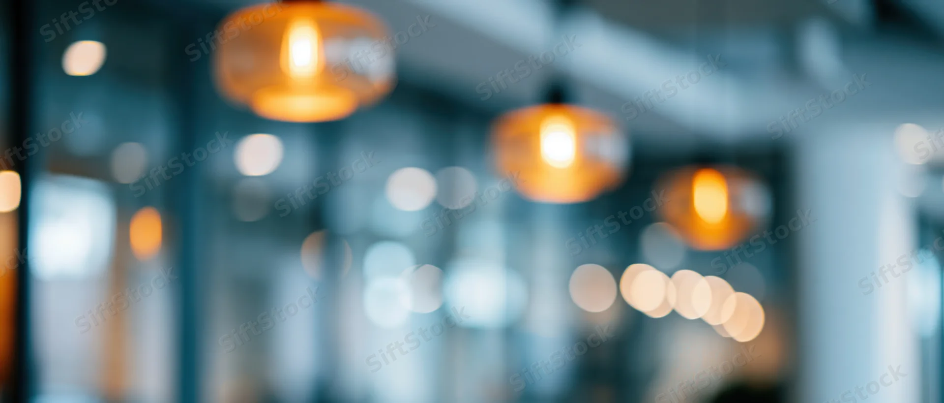 Blurred interior view with hanging warm lights creating soft glow in modern office space