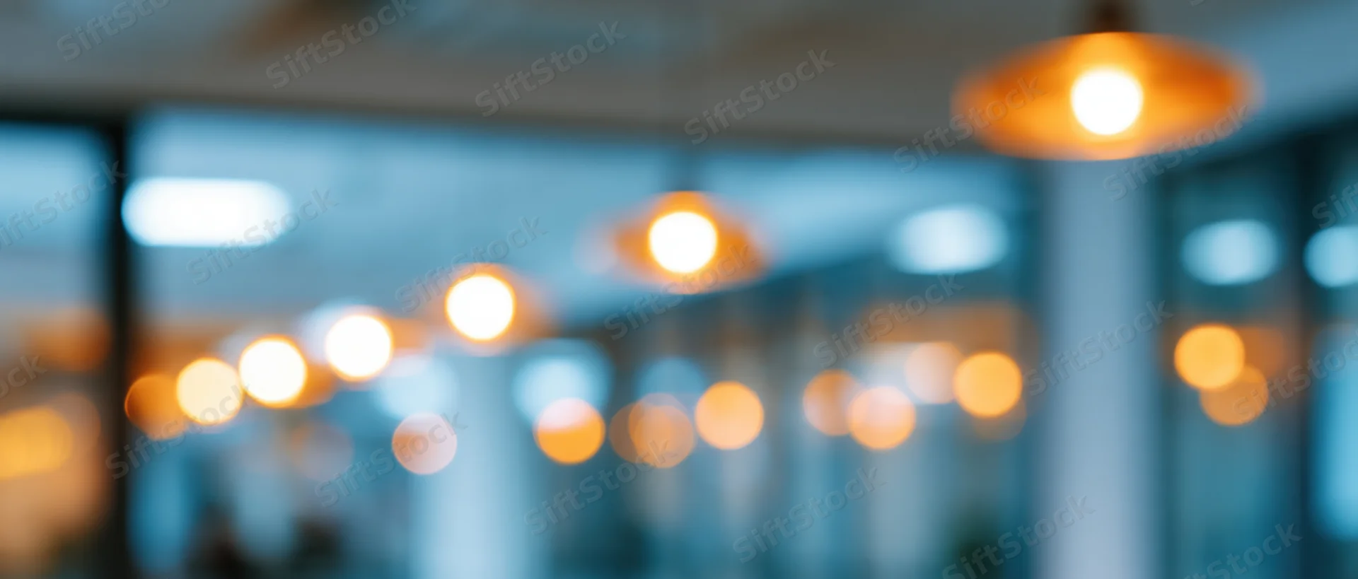 Blurred interior with warm pendant lights hanging from ceiling in modern office space