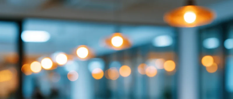 Blurred interior with warm pendant lights hanging from ceiling in modern office space