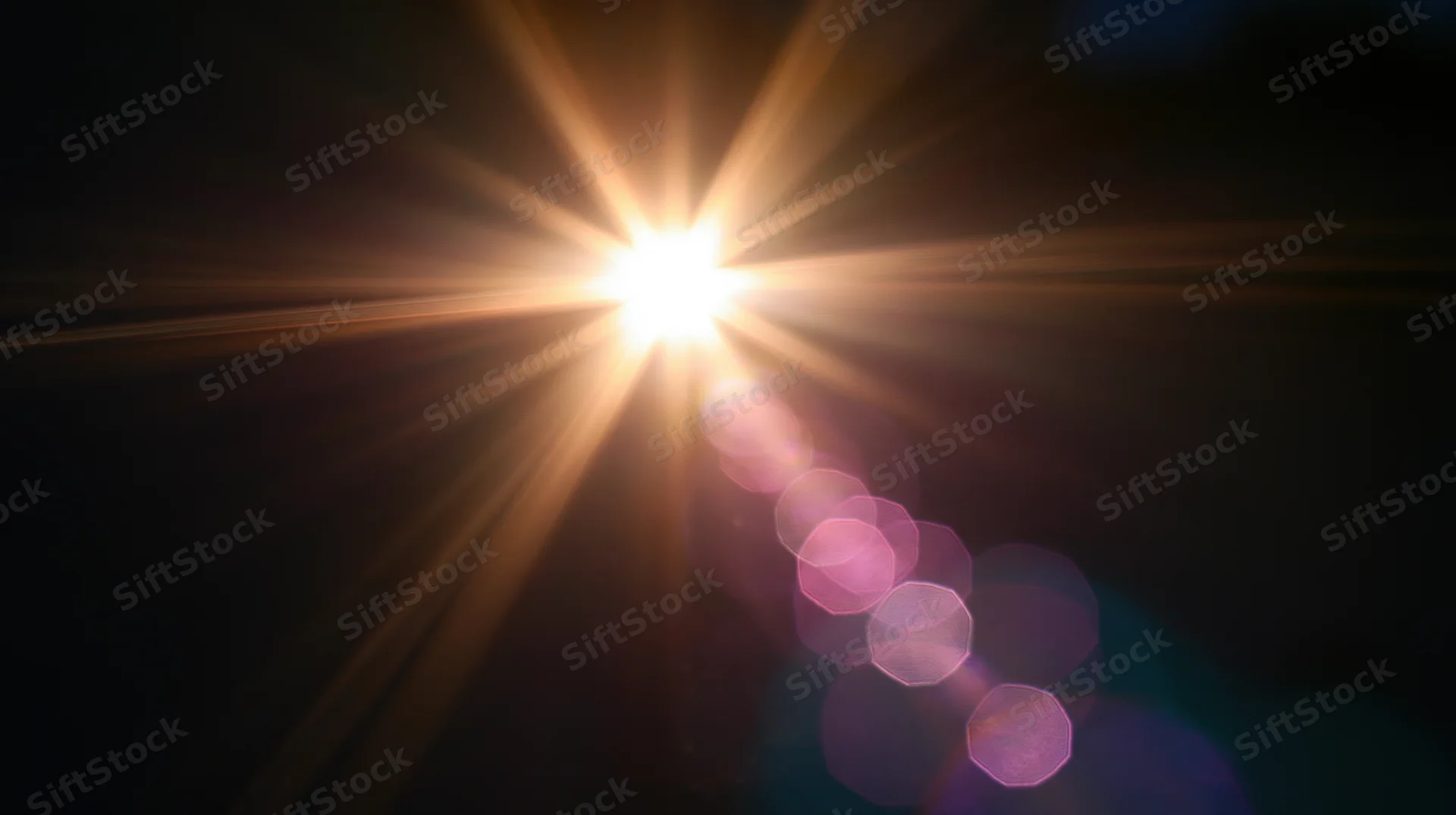 Bright light source emitting starburst rays and pink bokeh against dark background