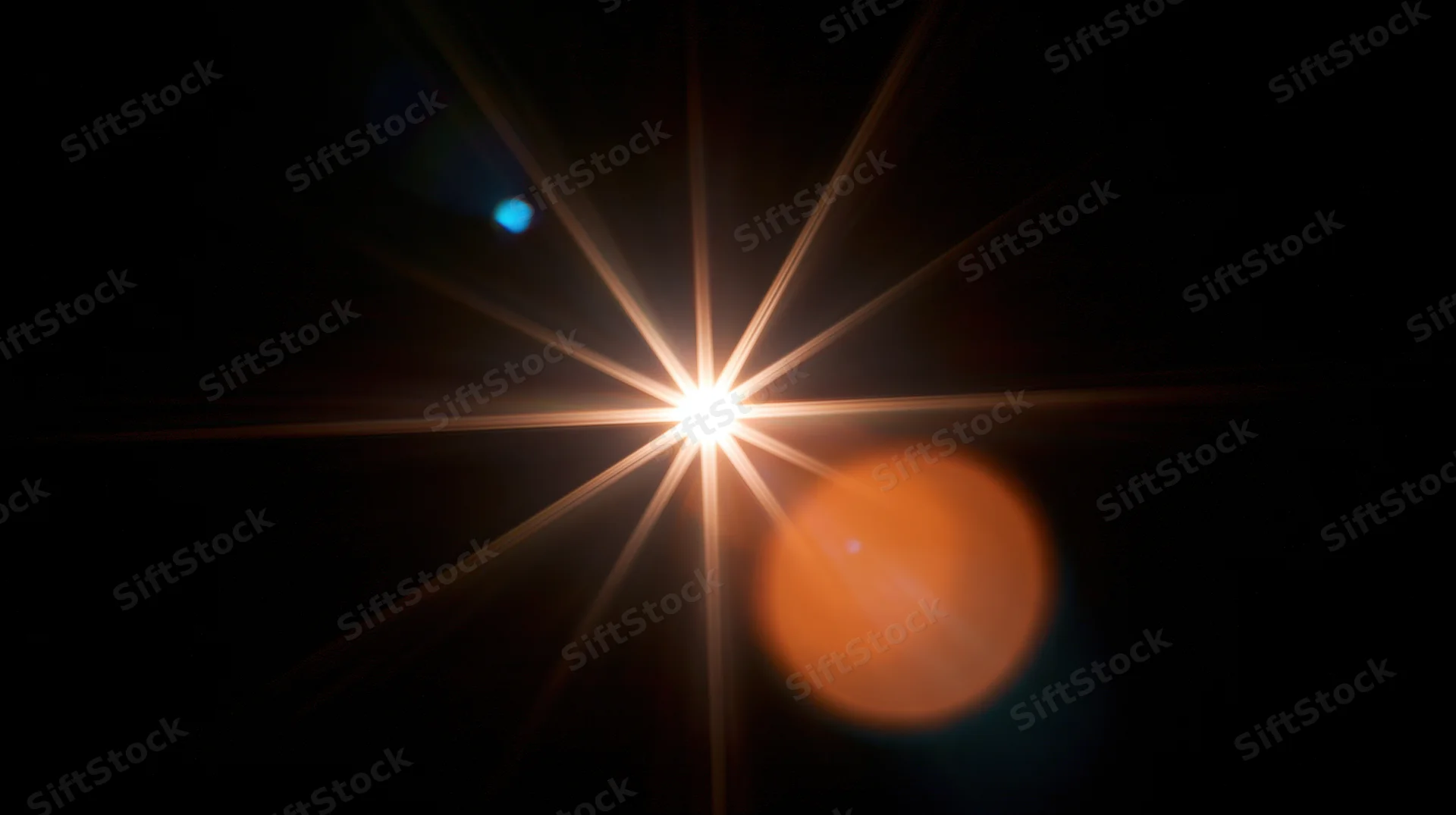 Bright starburst light with orange and blue bokeh against dark background