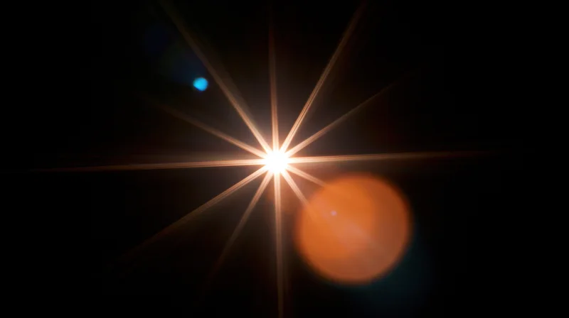 Bright starburst light with orange and blue bokeh against dark background