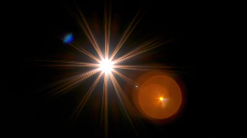 Bright star with lens flare and orange halo in dark space