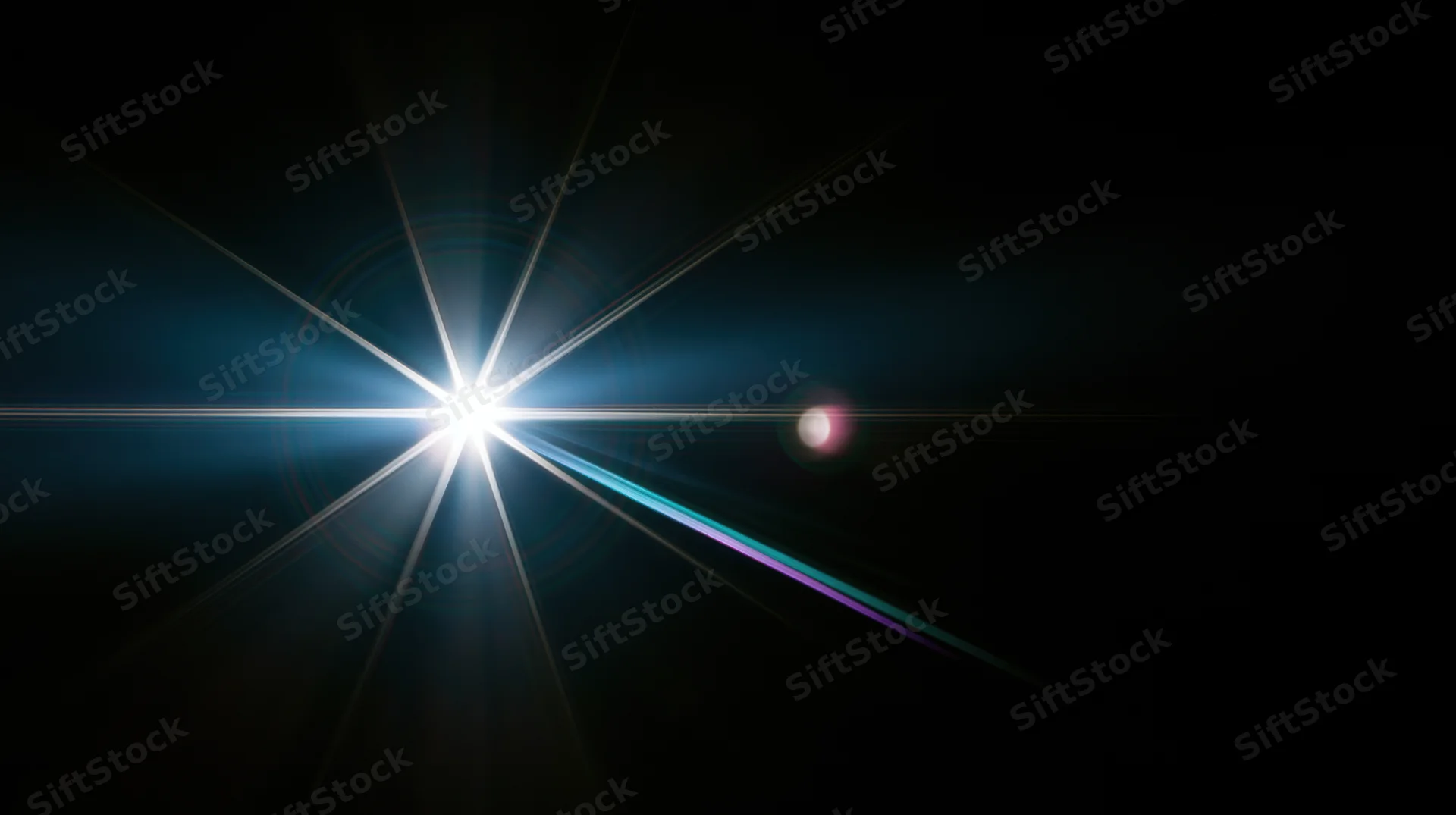 Bright starburst light flare radiating in dark space with colorful lens flares and beams