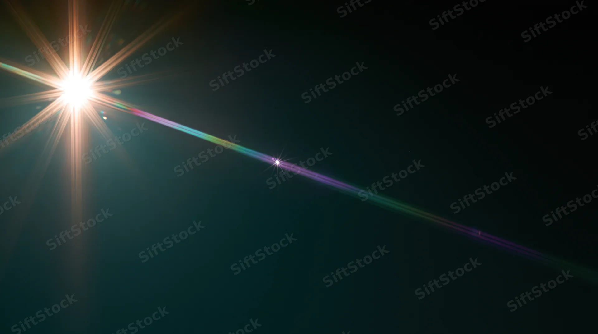 Bright light source creating lens flare and rainbow spectrum across dark background