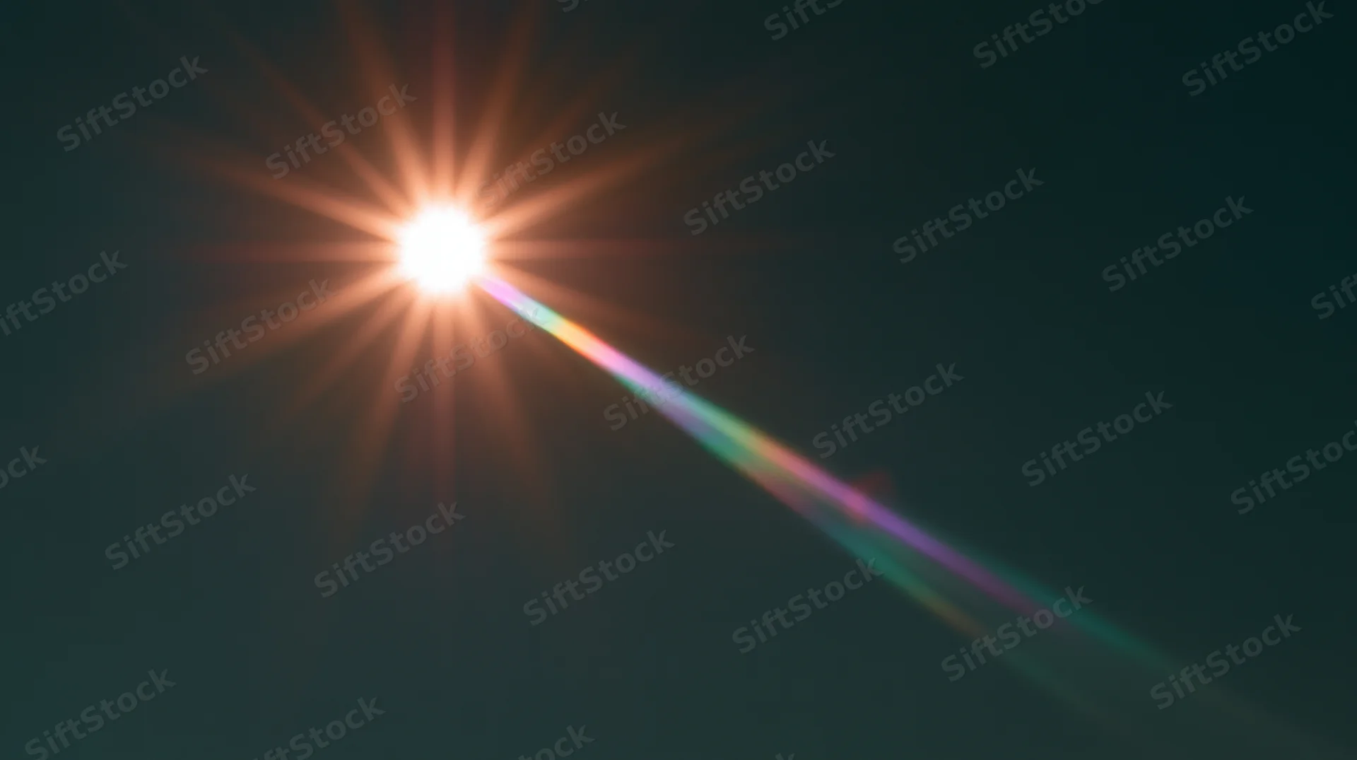 Bright sun with starburst lens flare and rainbow spectrum against dark sky