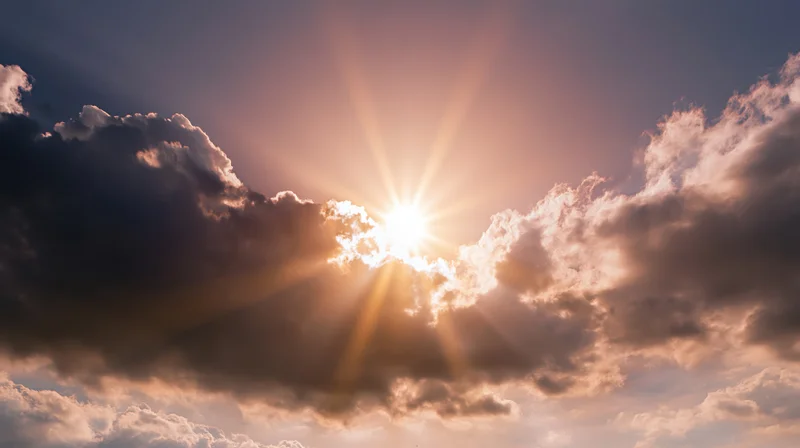 Sun shining through clouds in the sky at sunrise or sunset