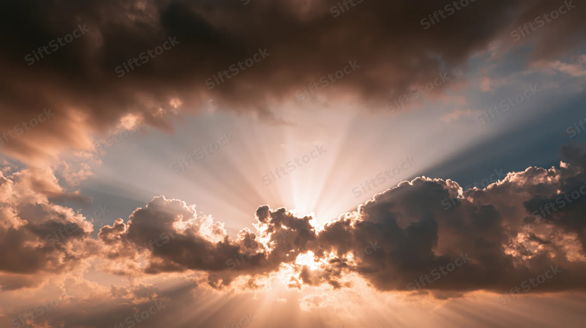 Sunlight breaking through dense clouds in a dramatic sky with golden rays and soft glow