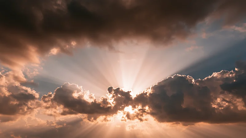 Sunlight breaking through dense clouds in a dramatic sky with golden rays and soft glow