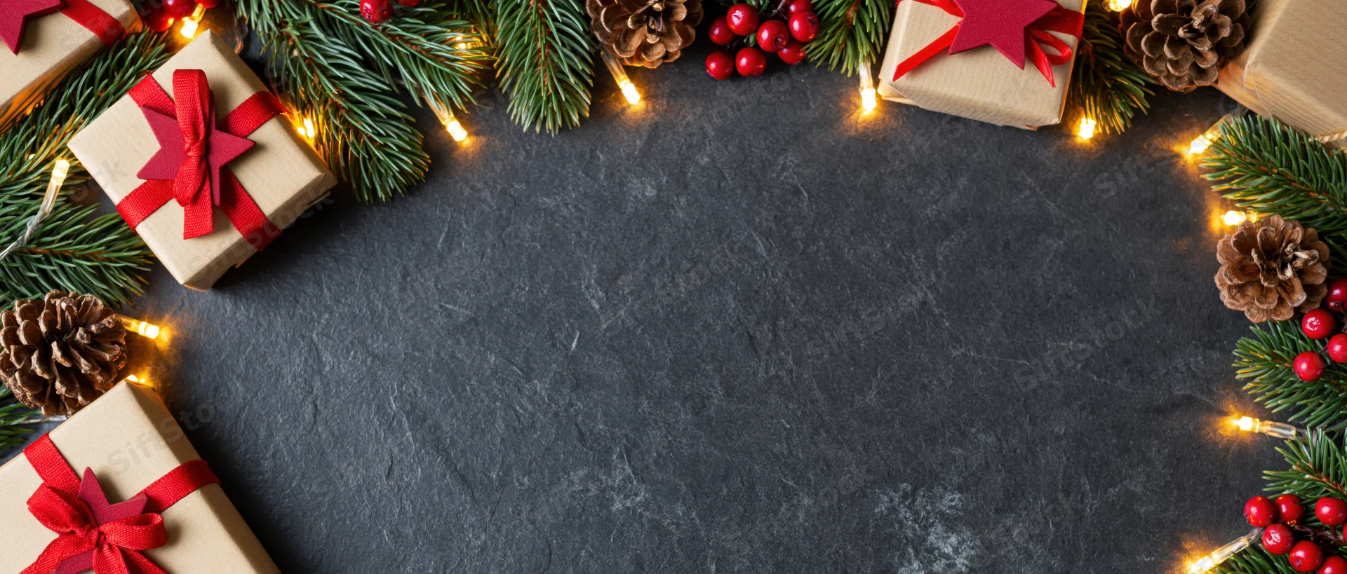 Christmas decorations and gifts arranged in a border around a dark surface with copyspace in the center
