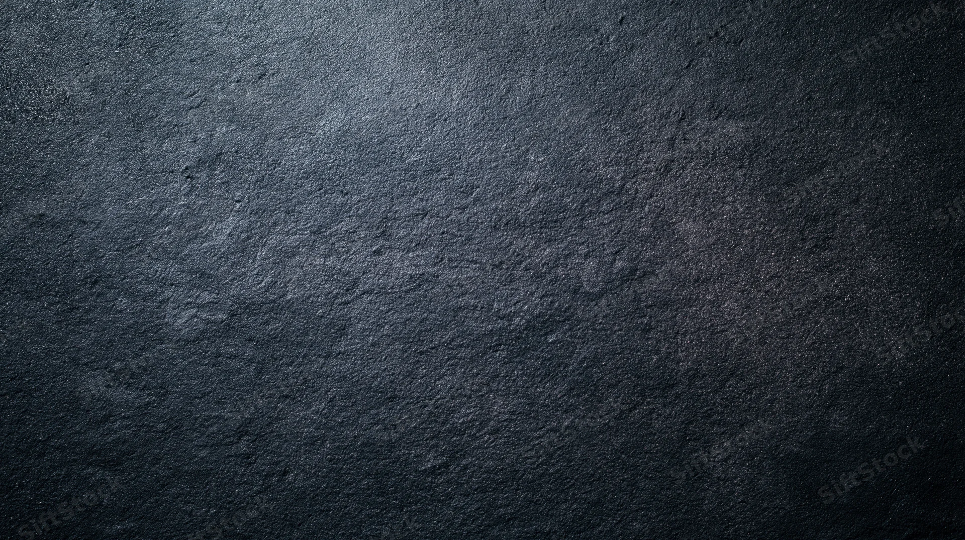 Dark textured stone surface with rough grainy finish and subtle shadows