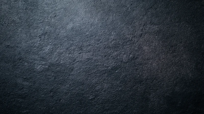 Dark textured stone surface with rough grainy finish and subtle shadows