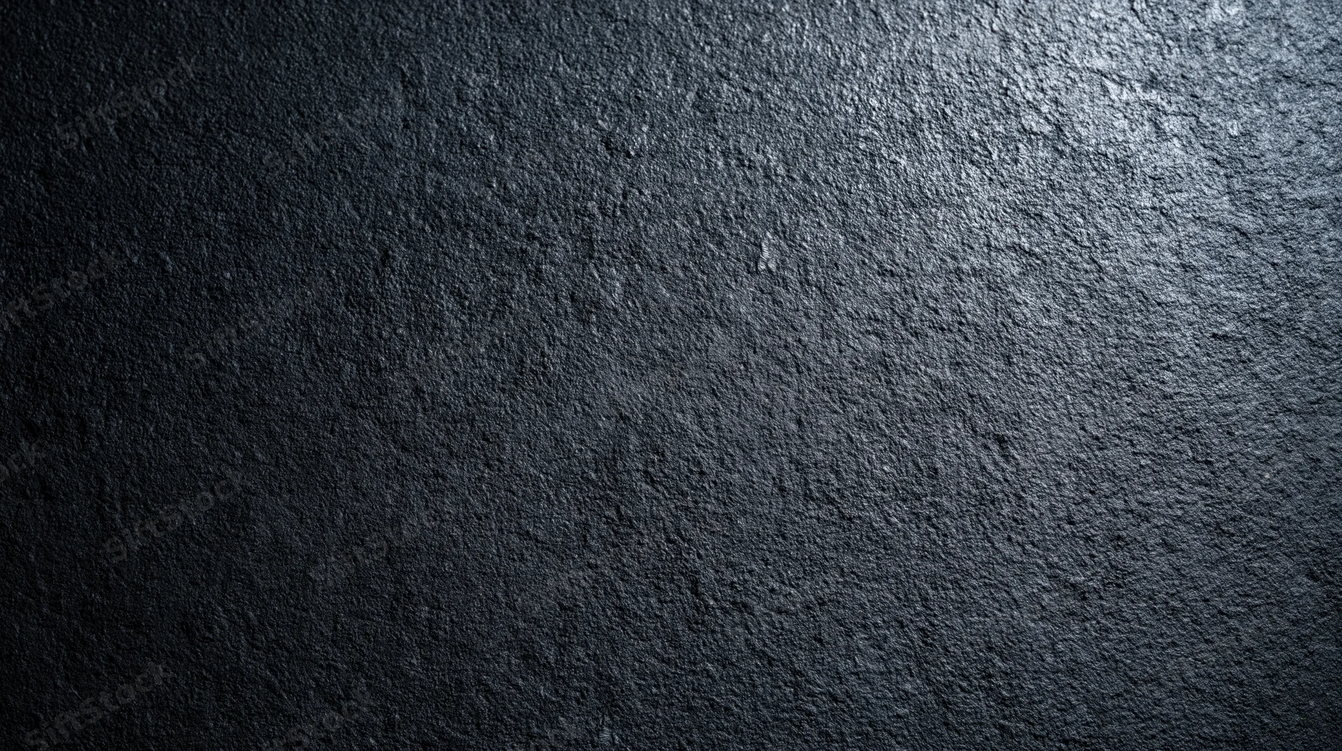Dark textured stone surface with rough uneven finish and subtle lighting gradient