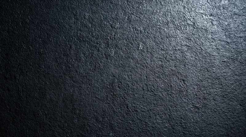 Dark textured stone surface with rough uneven finish and subtle lighting gradient