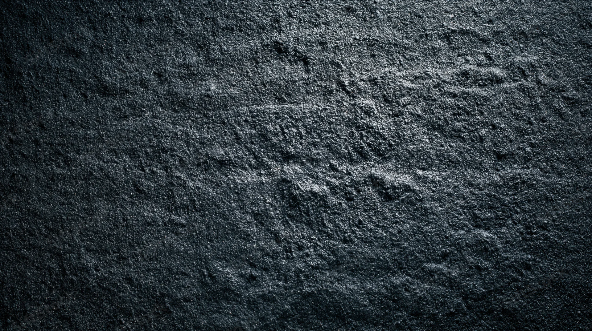 Dark textured stone surface with rough uneven grain and shadowed depth