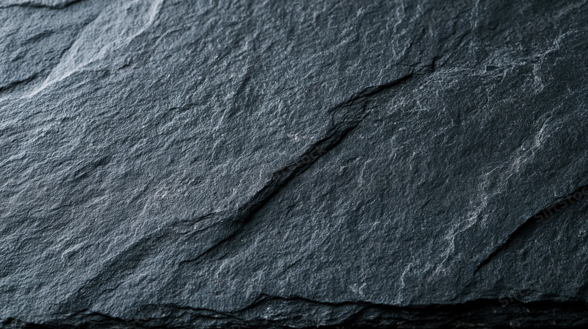 Close-up of dark slate rock surface with natural cracks and texture