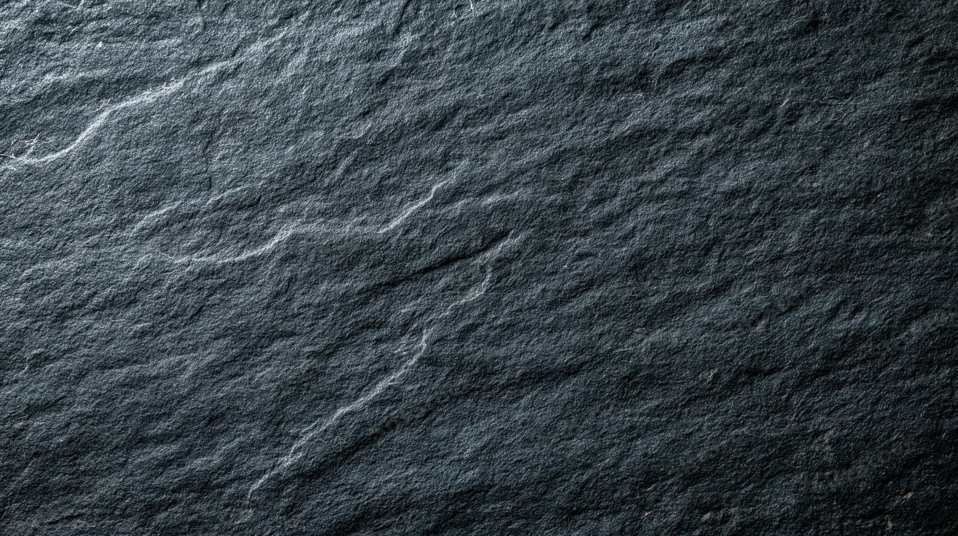 Closeup of dark slate stone surface with natural texture and grain pattern