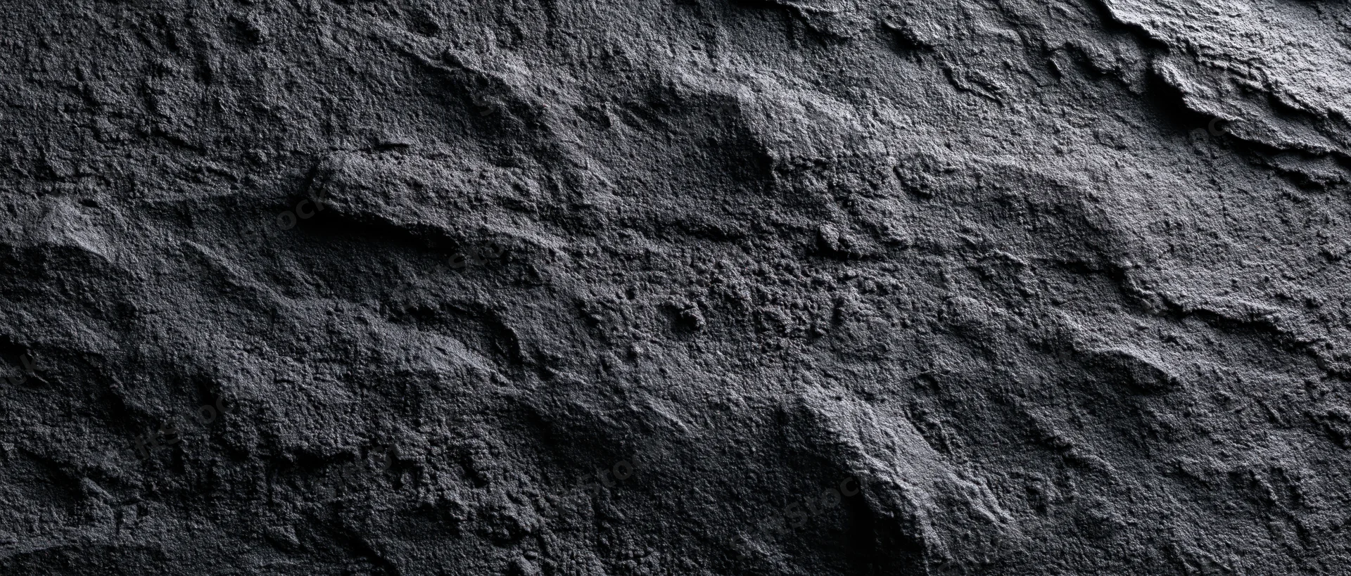 Closeup of dark rough stone surface with natural texture and layered formations