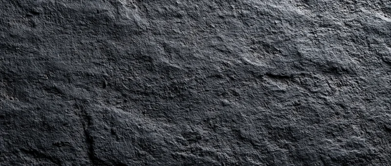 Closeup of dark rough stone surface with natural texture and uneven pattern