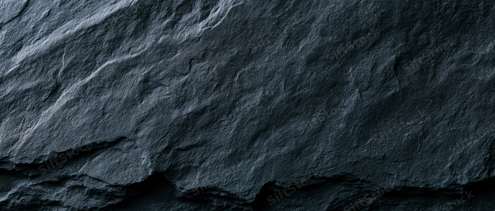 Dark slate rock surface with natural cracks and layered texture