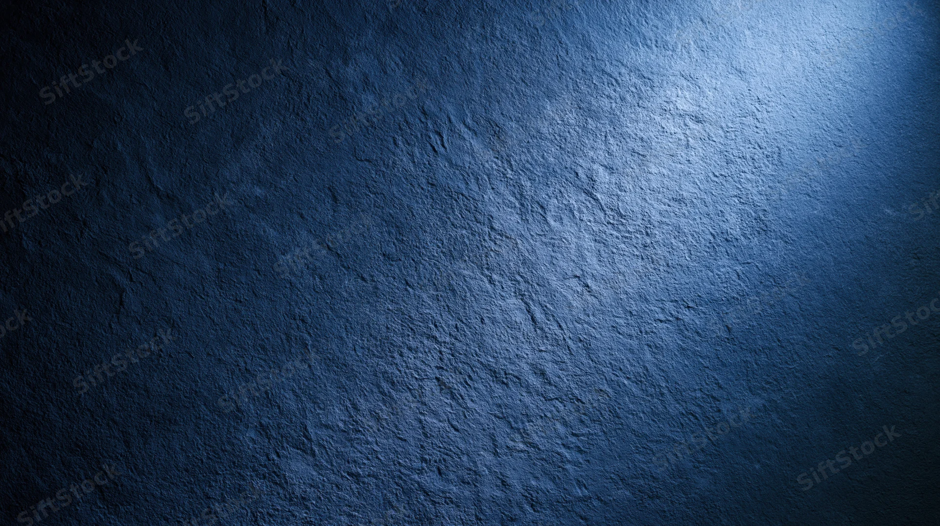 Textured blue stone wall illuminated by spotlight in dark interior
