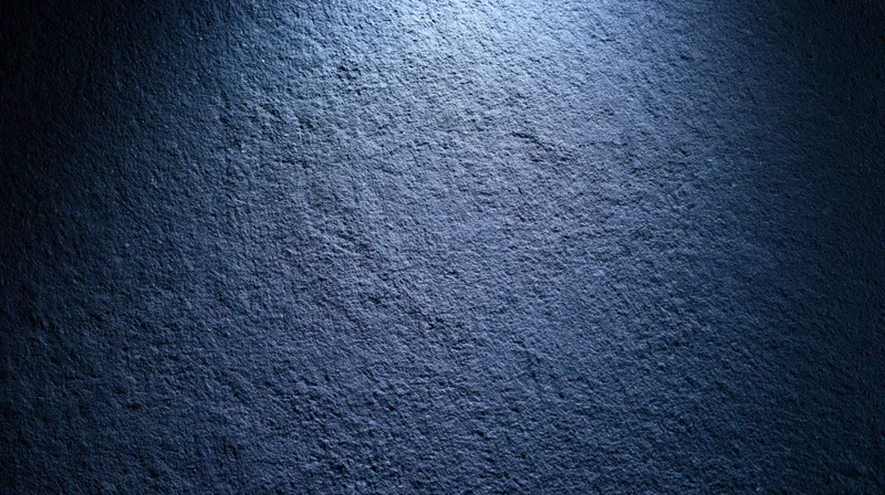 Textured blue concrete wall illuminated by a spotlight creating a gradient from light to dark